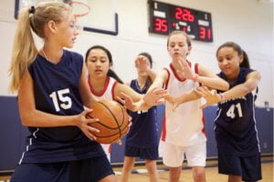 Female pupils playing indoor basketball